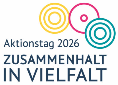 Dargestellt ist das Logo der Initiative kulturelle Integration, das aus drei bunten Kreisen besteht. Einem Gelben, Pinken und Petrolfarbenen. Darunter steht: Aktionstag 2026. Zusammenhalt in Vielfalt.