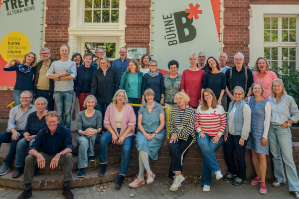 Personen stehen in zwei Reihen freundlich in die Kamera blickend vor dem Stadtteilkulturzentrum B*Treff Altona