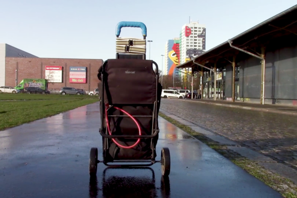 ein sogenannter Hackenporsche steht auf einer Straße vermutlich in einem Industriegebiet, im Hintergrund Autos, Gebäude und zwei Hochhäuser