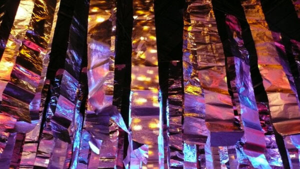 Von Diskolicht beleuchtete silberne Lamettastreifen, die von der Decke hängen