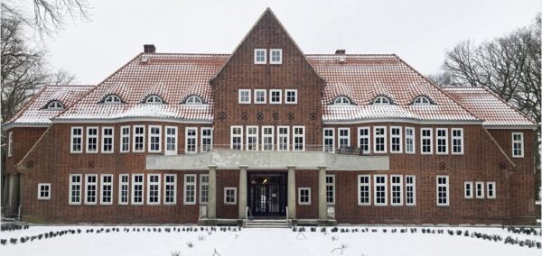 Auf dem Foto ist aus einer frontalen Perspektive die Villa Bondenwald in Hamburg-Niendorf abgebildet. Sowohl das Dach als auch der Vorgarten ist durch Schnee bedeckt. Das Gebäude ist ein großes, rotes Backsteingebäude mit einem Walmdach und jeweils zwei Seitenflügeln.